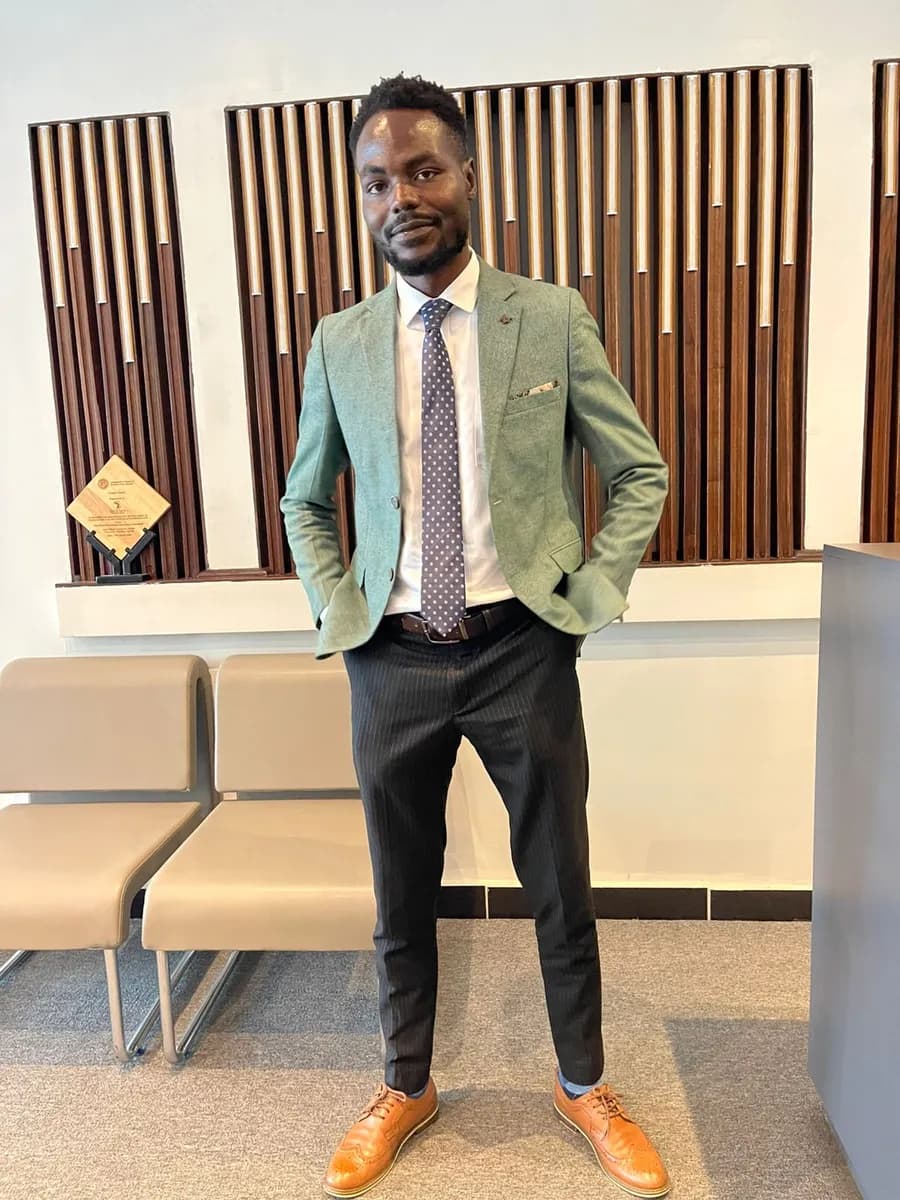 James Okach, Founder and CEO of Rahey AI, standing with his hands in his pockets, in a green jacket and a patterned tie